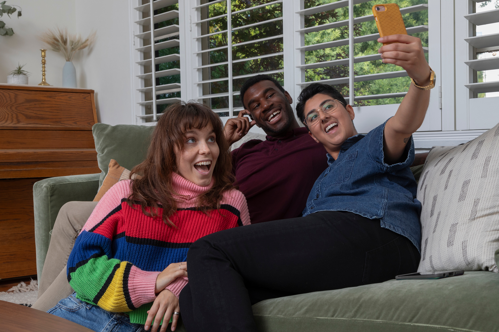 Stylish queer friends hanging out on the couch together